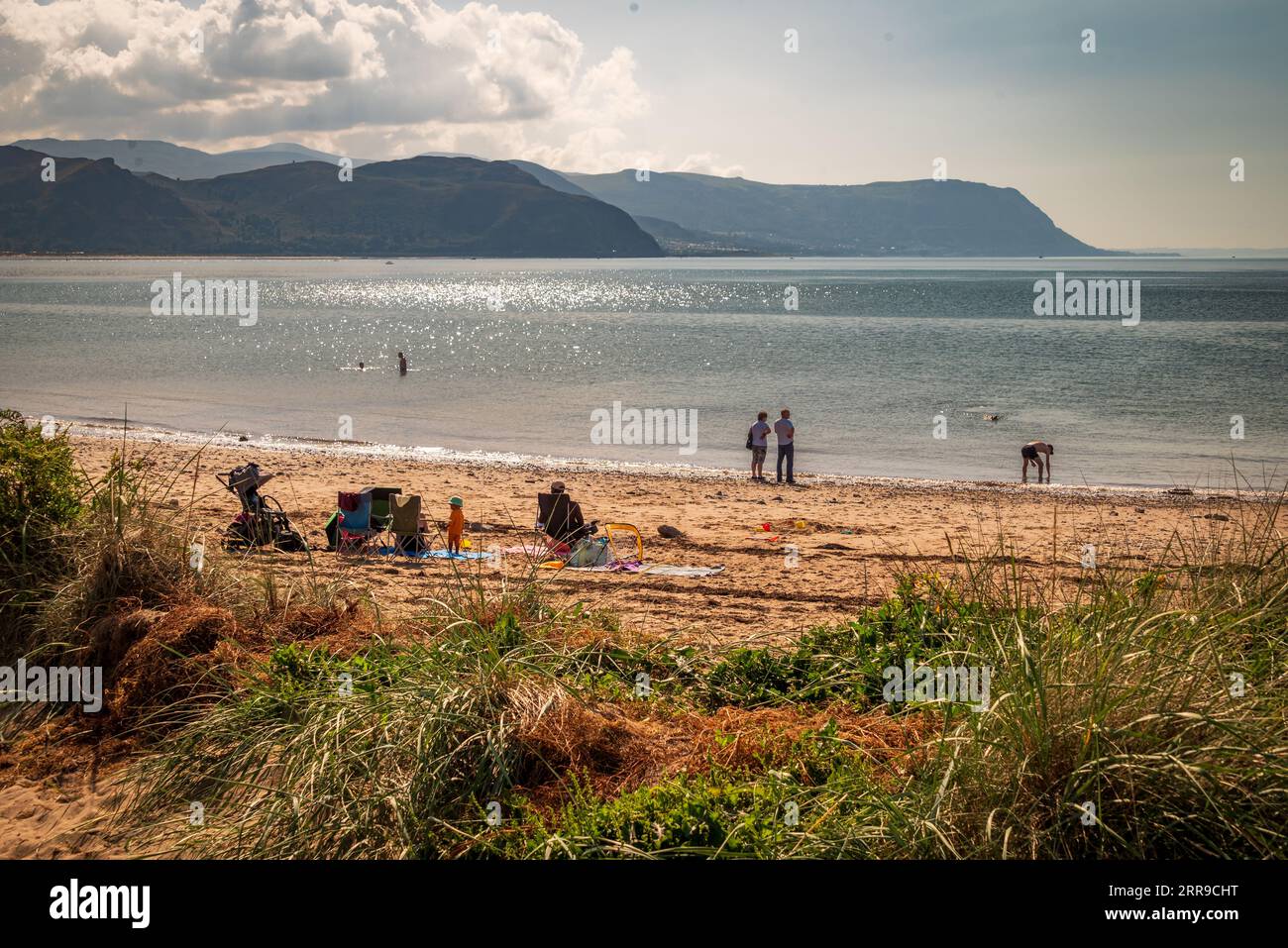 Familien in der Sonne an der Westküste von Llandudno, Nordwales, mit Blick auf Conwy Bay. Stockfoto