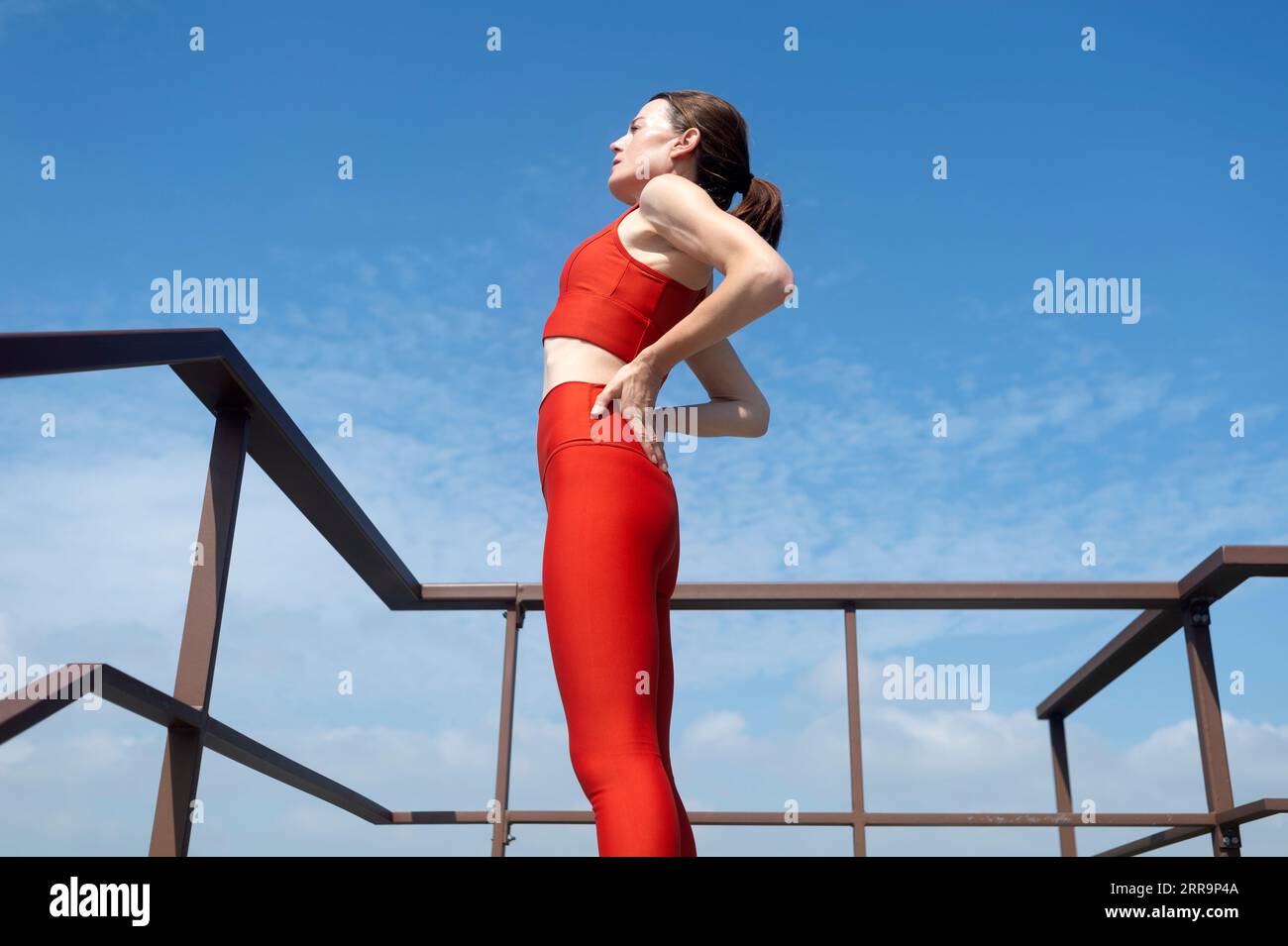 Eine Athletin, die pausiert, um ihre Rückenschmerzen zu lindern Stockfoto