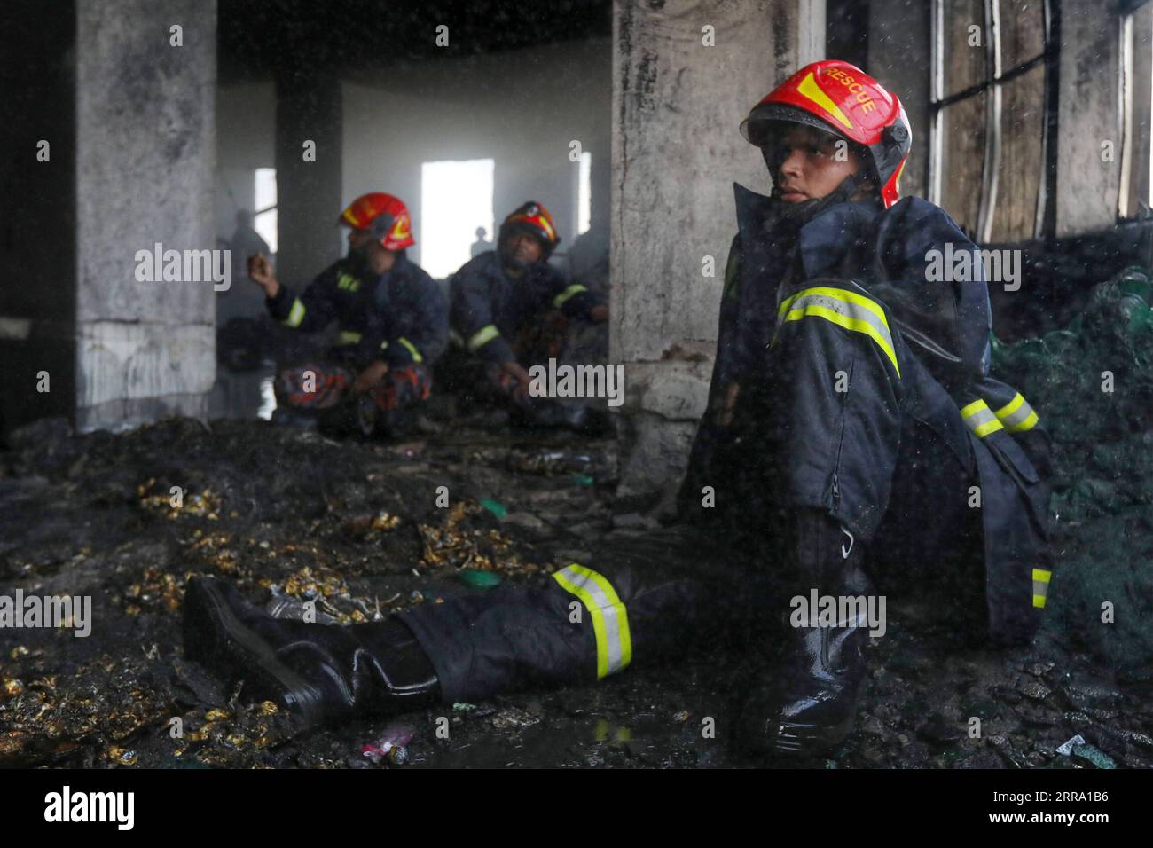 210709 -- NARAYANGANJ BANGLADESCH, 9. Juli 2021 -- Feuerwehrleute machen am 9. Juli 2021 eine Pause an der Feuerstelle einer Saftfabrik in Narayanganj am Stadtrand von Dhaka, Bangladesch. Mindestens 52 Menschen sind gestorben, als ein großes Feuer einen zweiten Tag lang in der Saftfabrik in Narayanganj wütete. BANGLADESCH-NARAYANGANJ-FACTORY-FIRE-SECOND DAY SALIM PUBLICATIONXNOTXINXCHN Stockfoto