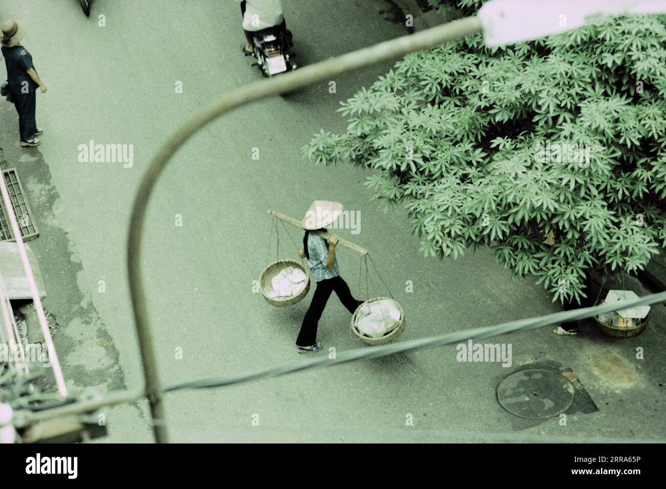 Vietnamesin, die Körbe über die Straße trägt Stockfoto