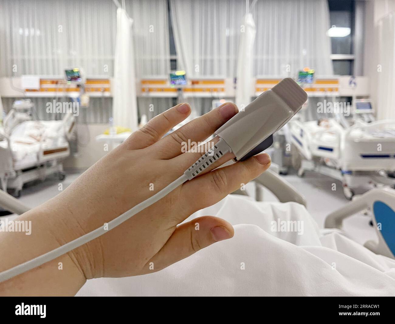 Im Krankenhaus Kranker auf dem Bett. Herzfrequenzmessgerät ist am Finger, Nahaufnahme der Hand Stockfoto