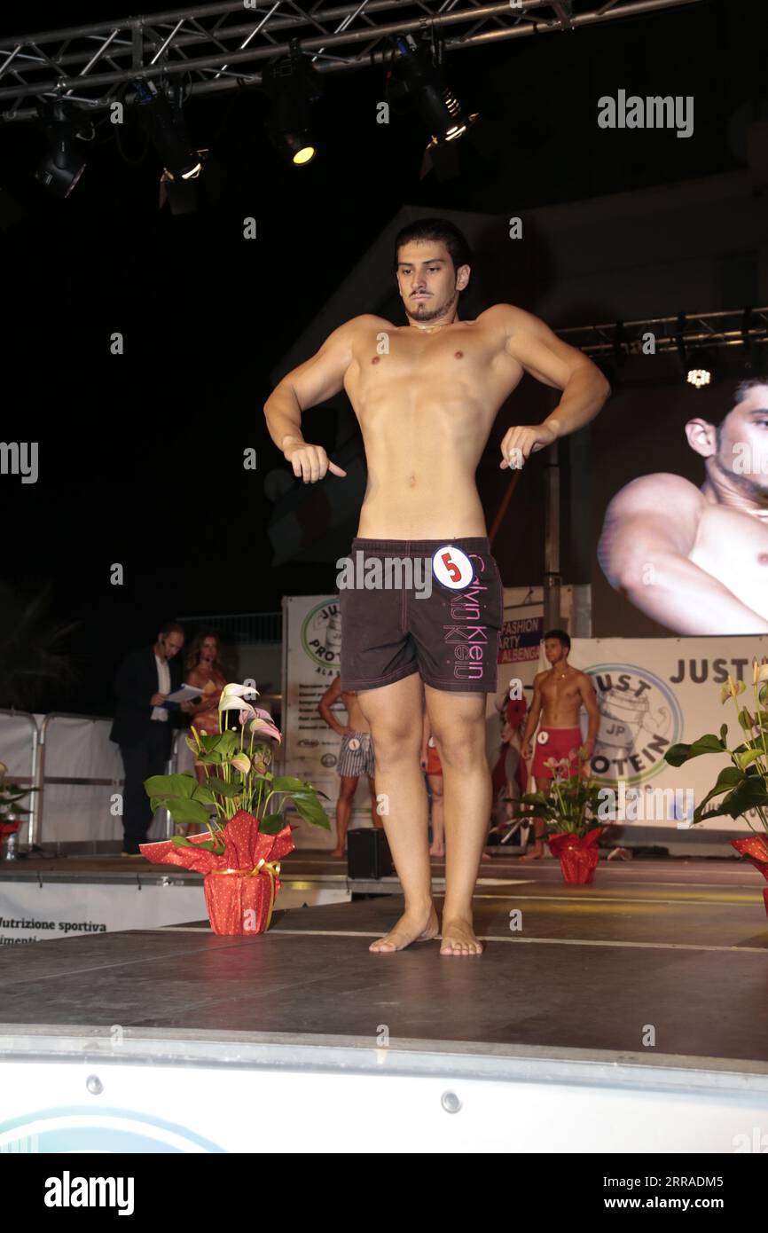 Die abendliche Mode- und Bodybuilding-Show mit stilvollen Jugendlichen auf dem Catwalk zeigt trendige Outfits und sportliche Körperteile. Stockfoto