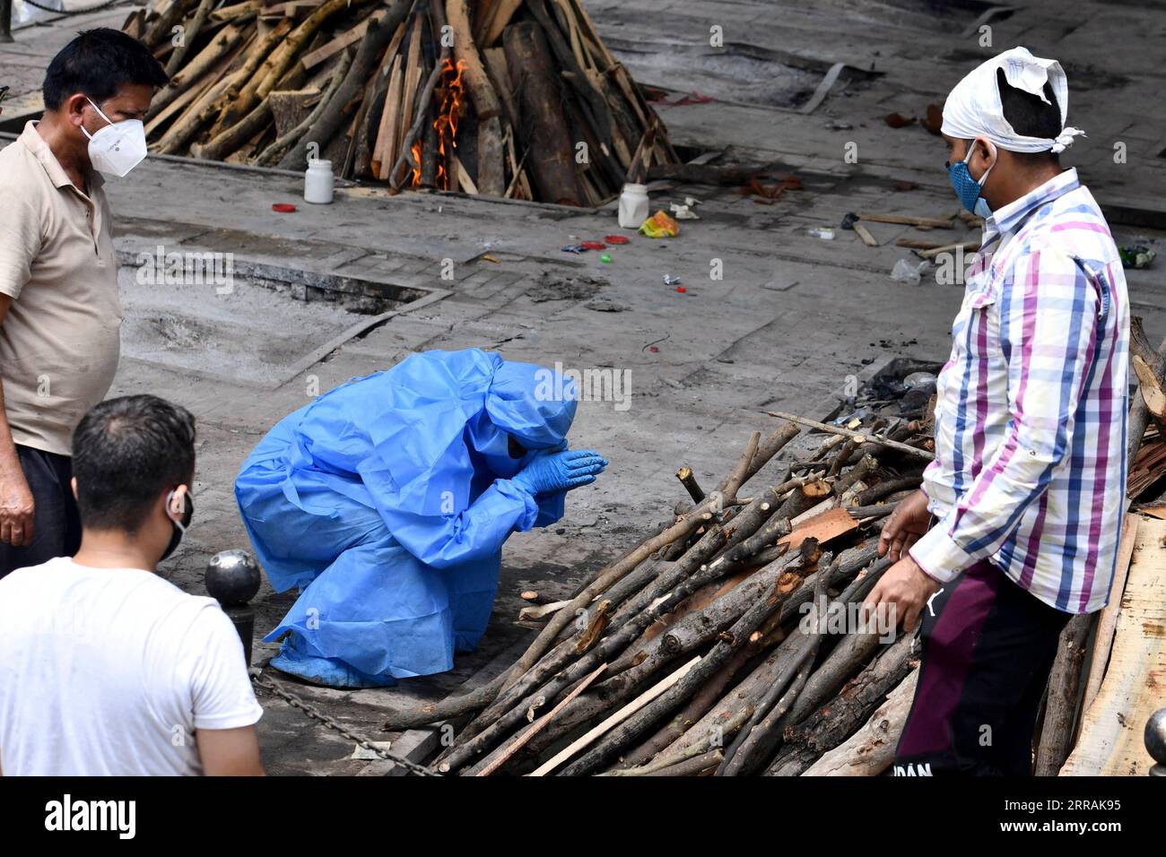 210805 -- PEKING, 5. August 2021 -- Ein Familienmitglied, Das einen Schutzanzug trägt, betet vor dem Pyre zu seinem Verwandten, bevor er in einem Krematorium in Neu-Delhi, Indien, am 21. Mai 2021 eingeäschert wird. Laut Daten der Johns Hopkins University haben die weltweiten COVID-19-Fälle am Mittwoch 200 Millionen überschritten. Die globale Fallzahl betrug 200.014.602, mit 4.252.873 Todesfällen weltweit, bis 15:21 Uhr Ortszeit 1921 GMT, zeigte die Daten. GLOBALE COVID-19-FÄLLE-SURPASS-200 MLN ParthaxSarkar PUBLICATIONxNOTxINxCHN Stockfoto