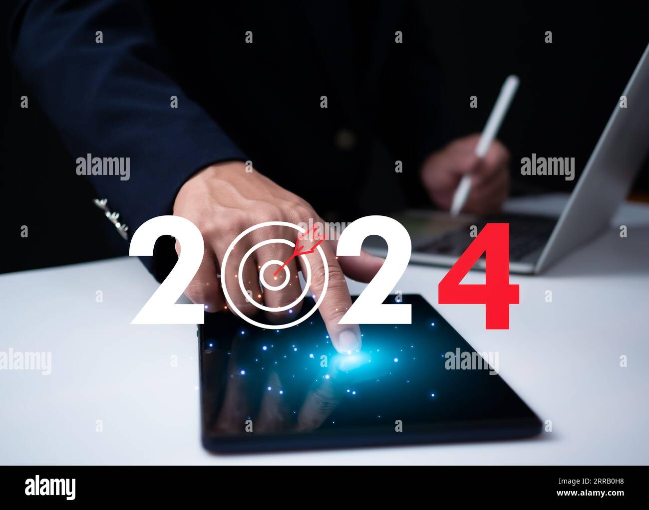 Ein Geschäftsmann, der auf das Tablet zeigt und ein Dartboard-Symbol mit Zahlen zeigt, stellt die Zielvorgabe für 2024 dar. Startup-Konzept, Finanzplanung, Entwicklung Stockfoto