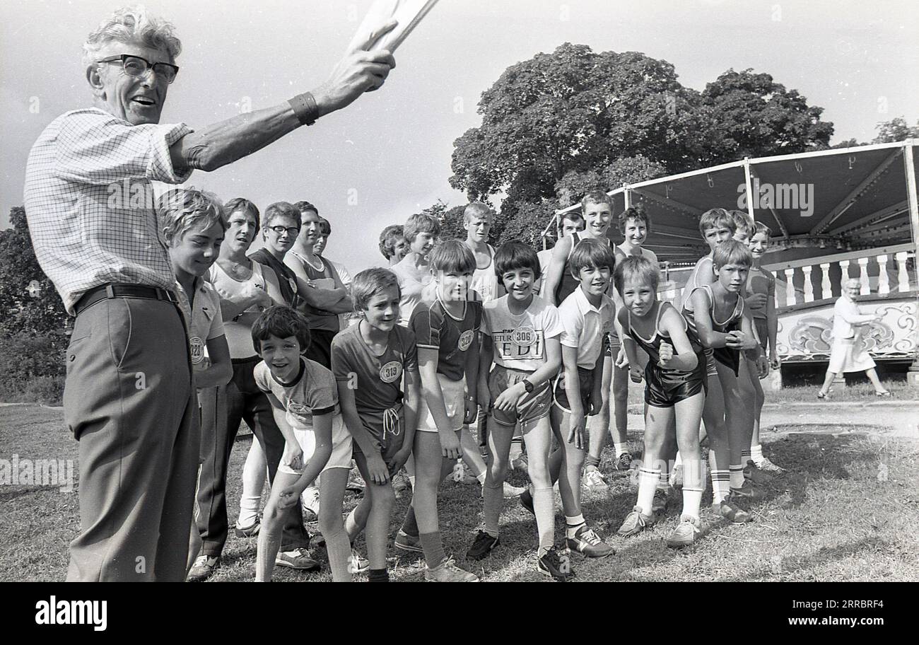 1981, draußen auf einem Feld, ein Mann, der papes für den Start des Kinder-Laufrennens hält, England, Großbritannien. Stockfoto