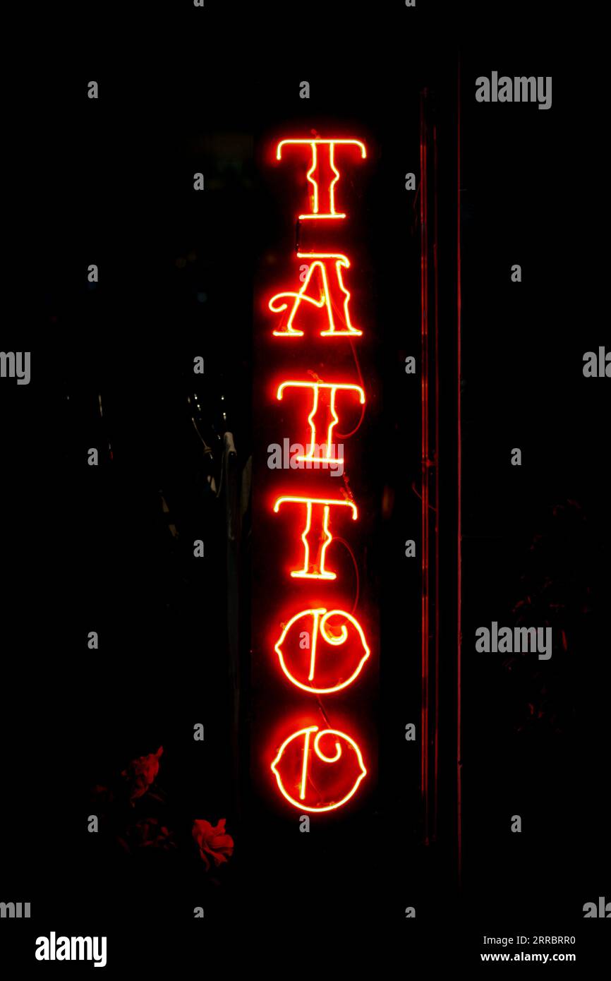 Tattoos-Schild in roten Neonlichtern auf schwarzem Hintergrund Stockfoto