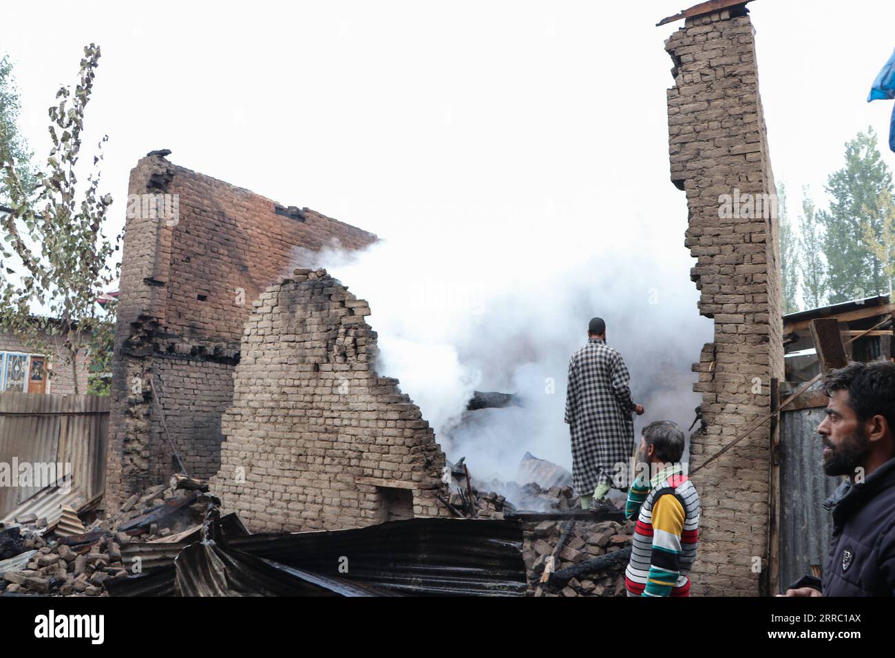 211012 -- SRINAGAR, 12. Oktober 2021 -- Menschen untersuchen die Trümmer eines Hauses, das während einer Schießerei in einem Dorf im Bezirk Shopian beschädigt wurde, etwa 62 km südlich von Srinagar, der Sommerhauptstadt des von Indianern kontrollierten Kaschmirs, 12. Oktober 2021. Drei Militante wurden am Dienstag in einem heftigen bewaffneten Kampf mit Regierungstruppen im von Indianern kontrollierten Kaschmir getötet, sagte die Polizei. KASCHMIR-SRINAGAR-GUNFIGHT JavedxDar PUBLICATIONxNOTxINxCHN Stockfoto