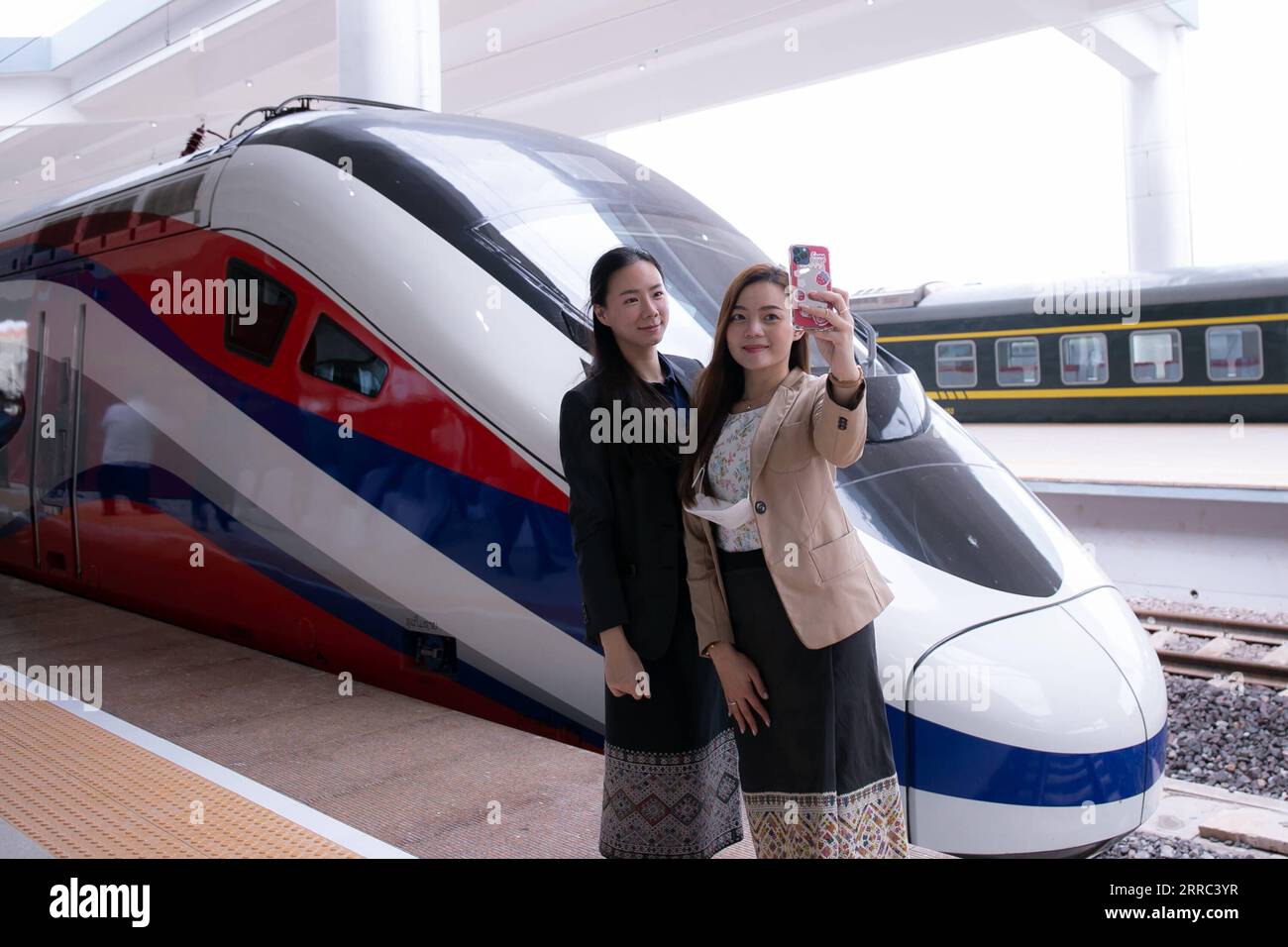 211016 -- VIENTIANE, 16. Oktober 2021 -- zwei Frauen posieren für Fotos mit dem Zug Lane Xang Emu am Bahnhof Vientiane der China-Laos-Eisenbahn in der laotischen Hauptstadt Vientiane, 16. Oktober 2021. Der stromlinienförmige, nach China-Standard gefahrene Hochgeschwindigkeitszug, oder elektrische Triebzüge der EWU für die China-Laos-Eisenbahn, erreichte am Samstag die neu gebaute Vientiane-Station der China-Laos-Eisenbahn. Der EWU-Zug wurde offiziell an die Laos-China Railway Co., Ltd., ein Gemeinschaftsunternehmen mit Sitz in der laotischen Hauptstadt Vientiane, geliefert, das für den Bau und Betrieb der Eisenbahn zuständig ist, und zwar im Rahmen einer Übergabereise im Bahnhof mit Th Stockfoto