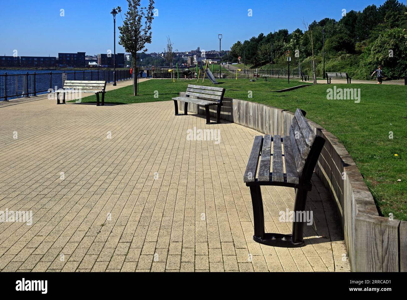 Barry Island angenehmer Sitzbereich mit drei Holzbänken an den alten Docks, mit Spielplatz dahinter. September 2023 Stockfoto