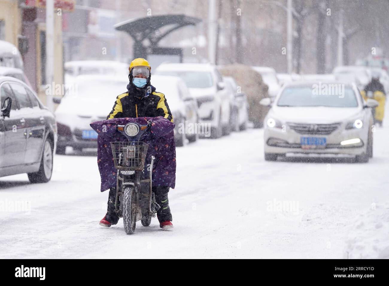 211122 -- HARBIN, 22. November 2021 -- Ein Kurier fährt auf einer schneebedeckten Straße in Harbin City, nordöstliche chinesische Provinz Heilongjiang, 22. November 2021. Schwere Schneefälle trafen in letzter Zeit viele Teile von Heilongjiang. Mitarbeiter verschiedener Sektoren trotzen eisigen Böen und Schneeflocken, um die normale Verfügbarkeit wesentlicher öffentlicher Dienste zu gewährleisten. CHINA-HEILONGJIANG-BLIZZARD CN WangxJianwei PUBLICATIONxNOTxINxCHN Stockfoto