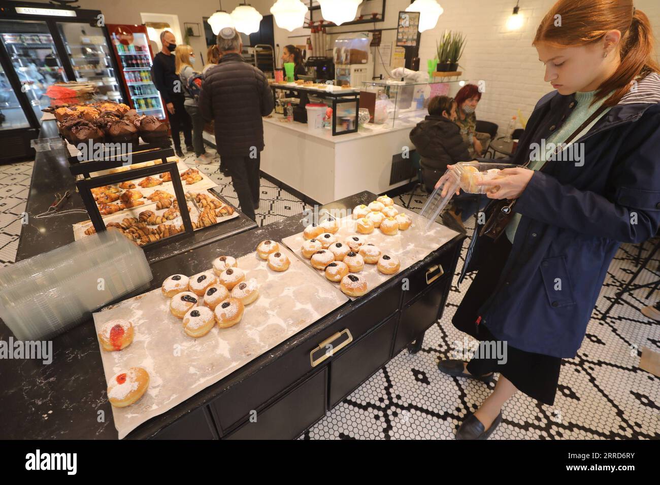 211206 -- JERUSALEM, 6. Dezember 2021 -- Eine Frau pickt Sufganiyots, runde Gelee-Donuts, die auf dem jüdischen Festival von Hanukka gegessen wurden, in einem Geschäft während Hanukkah in Jerusalem am 6. Dezember 2021. Foto: /Xinhua MIDEAST-JERUSALEM-HANUKKAH-DONUTS MuammarxAwad PUBLICATIONxNOTxINxCHN Stockfoto