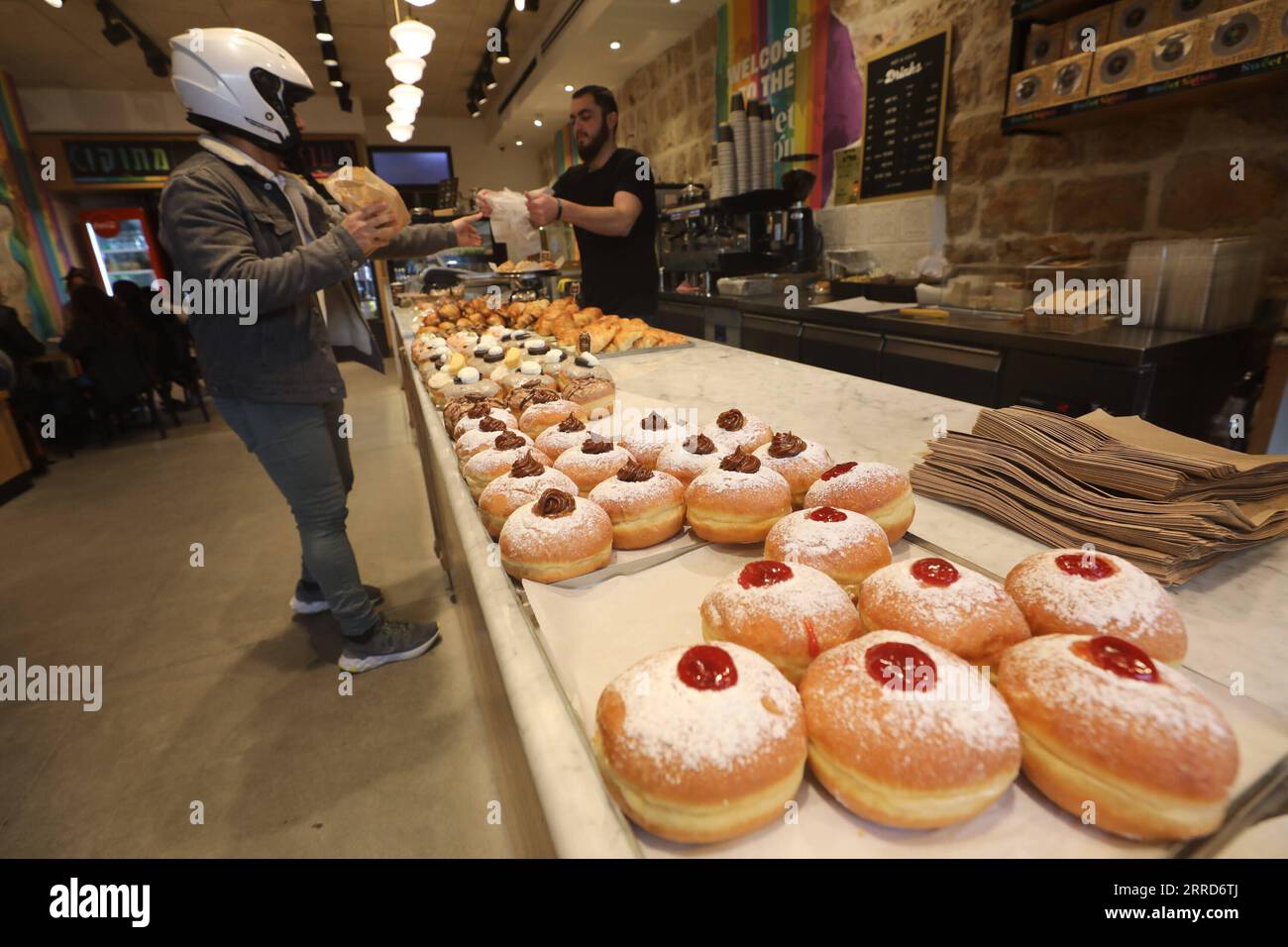 211206 -- JERUSALEM, 6. Dezember 2021 -- Ein Kunde kauft Sufganiyots, runde Gelee-Donuts, die auf dem jüdischen Festival von Hanukkah gegessen wurden, in einem Geschäft während Hanukkah in Jerusalem am 6. Dezember 2021. Foto: /Xinhua MIDEAST-JERUSALEM-HANUKKAH-DONUTS MuammarxAwad PUBLICATIONxNOTxINxCHN Stockfoto