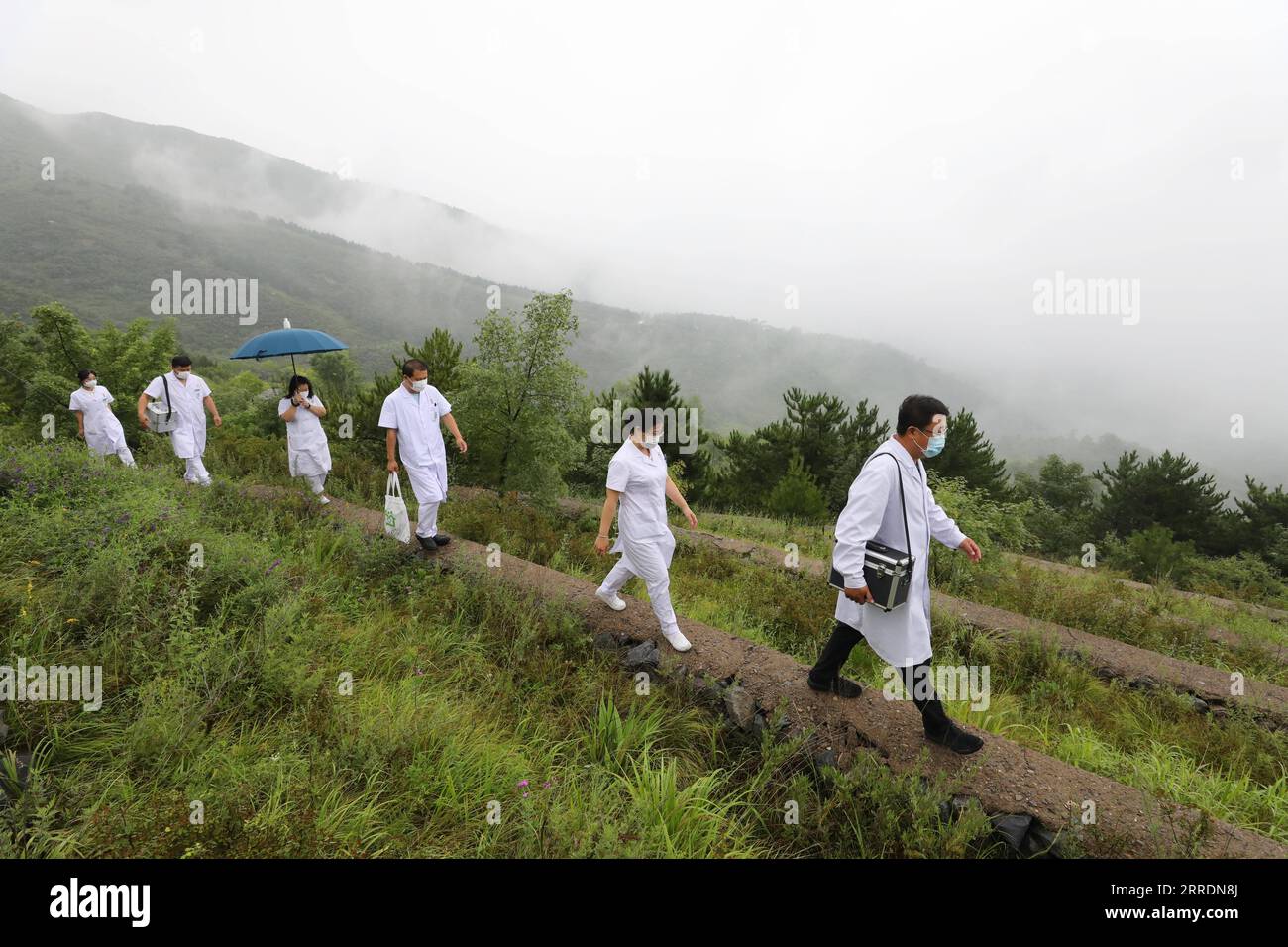 220104 -- PEKING, 4. Januar 2022 -- Wang Jinhui 1st R und seine Kollegen gehen im Juli 2020 auf einer Bergstraße. MIT überall in China: Die medizinischen Teams der Pekinger Berge CHINA-BEIJING-da ANSHAN-MEDICAL TEAMS CN Xinhua PUBLICATIONxNOTxINxCHN Stockfoto
