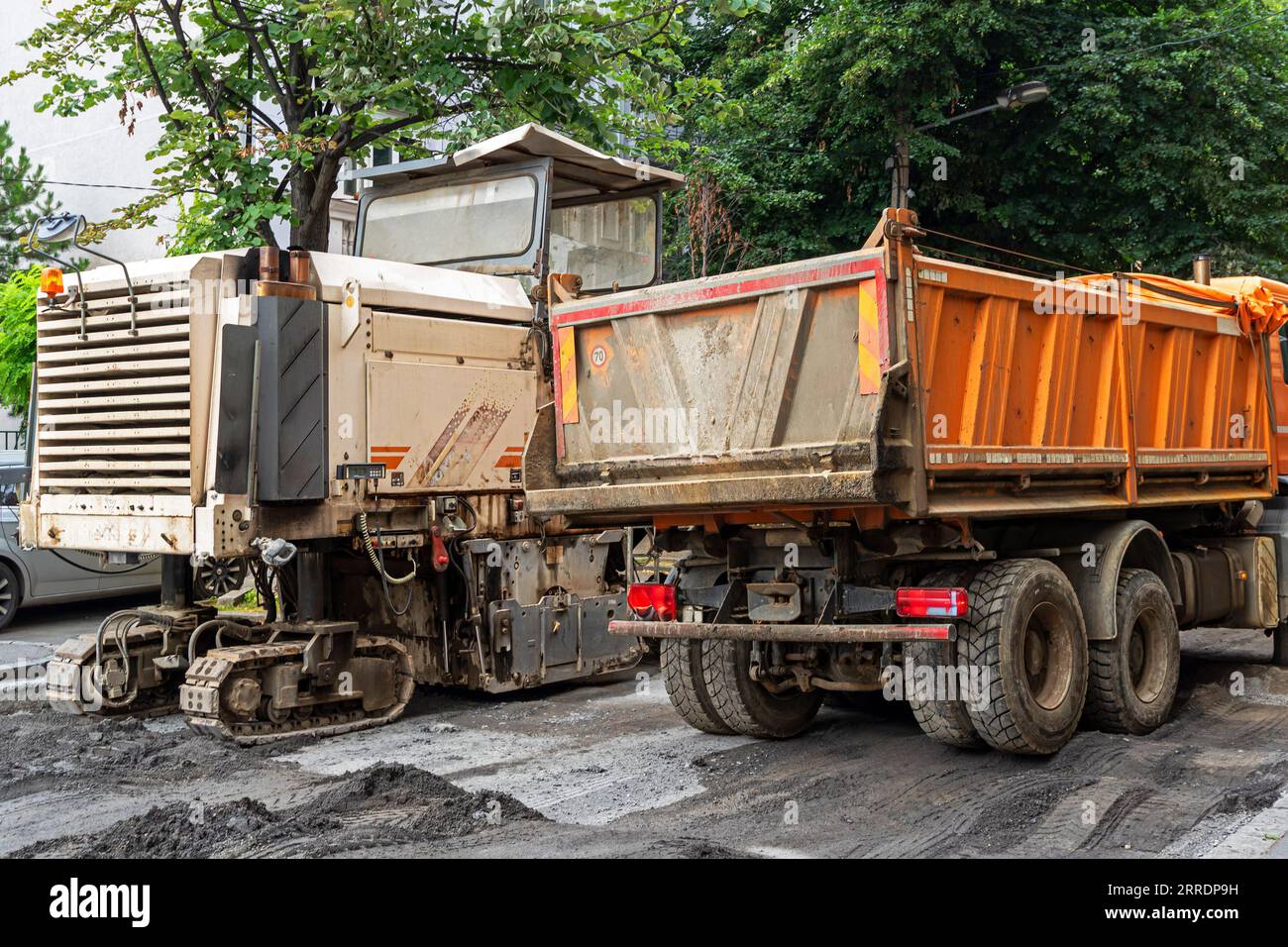 Maschine für Straßenbauarbeiten auf Asphalt neben einem Kipper-Lkw auf der Straße Stockfoto