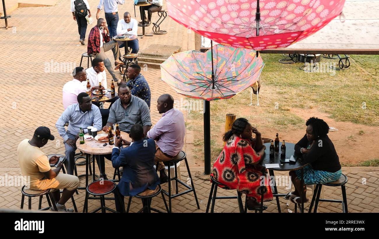 220125 -- KAMPALA, 25. Januar 2022 -- nach der Wiedereröffnung in Kampala, Uganda, am 24. Januar 2022, genießen die Leute Bier in einer Bar. Die allgemeine Ausgangssperre in der Nacht wurde am Montag in Uganda aufgehoben, was die vollständige Wiedereröffnung der Wirtschaft des Landes markierte. Einige Wirtschaftssektoren sind seit Monaten aufgrund der Pandemie geschlossen. Foto von /Xinhua UGANDA-KAMPALA-BARS-REOPENING HajarahxNalwadda PUBLICATIONxNOTxINxCHN Stockfoto
