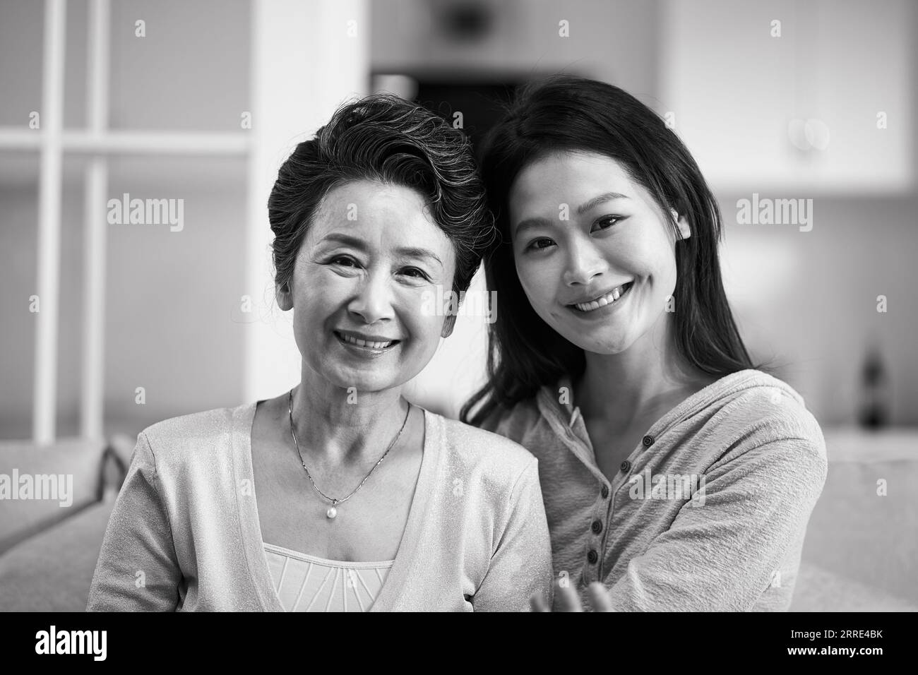 Porträt einer asiatischen Seniormutter und erwachsenen Tochter, die camra lächelnd ansieht, schwarz-weiß Stockfoto