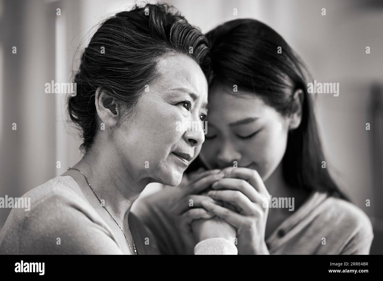 Junge asiatische Erwachsene Tochter tröstende ältere Mutter mit psychischen Erkrankungen, schwarz-weiß Stockfoto