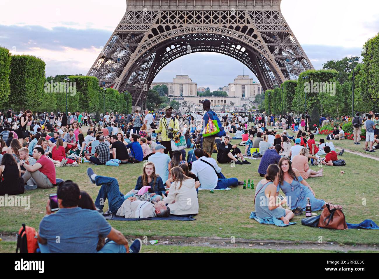 Paris, Souvenirverkäufer, die auf den Champs de Mars arbeiten, verkaufen Bier und Wein an Touristen, die am Abend ein Picknick machen und auf die Lichtshow im Eiffelturm warten Stockfoto