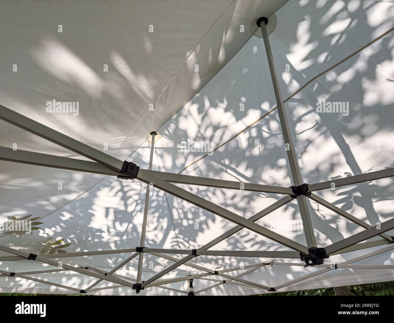 Weiße Markise im Garten mit unscharfem Schatten eines Baumes an sonnigen Sommertagen. Stockfoto