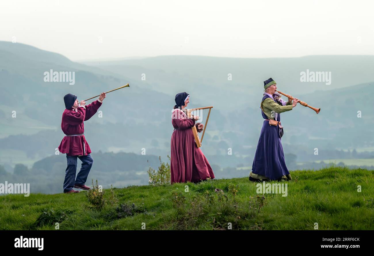 Musiker mit ihren Instrumenten aus dem 15. Jahrhundert, die Terry Mann mit einer Buisine, Jackie Phillips mit einer Harfe, und Lizzie Gutteridge spielt einen Alto Shawm auf dem Gelände von Bolton Castle in North Yorkshire, bevor er während der Medieval Music in the Dales auftritt, Englands Festival für mittelalterliche Musik, das vom 8. bis 10. September stattfindet. Bilddatum: Donnerstag, 7. September 2023. Stockfoto