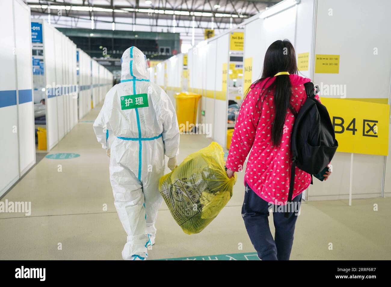 220402 -- SHANGHAI, 2. April 2022 -- Ein medizinischer Arbeiter hilft, das Gepäck eines Patienten in der Quarantänezone des Shanghai New International Expo Center im ostchinesischen Shanghai zu tragen. Shanghais größter provisorischer Quarantäneort für leichte Fälle und asymptomatische Träger unter dem jüngsten COVID-19-Wiederaufleben ist am Donnerstag in Betrieb genommen worden. Die Anlage, die vom Shanghai New International Expo Center umgebaut wurde, hat eine Kapazität von über 15.000 Betten. CHINA-SHANGHAI-QUARANTINE VENUE-OPERATION CN DINGXTING PUBLICATIONXNOTXINXCHN Stockfoto