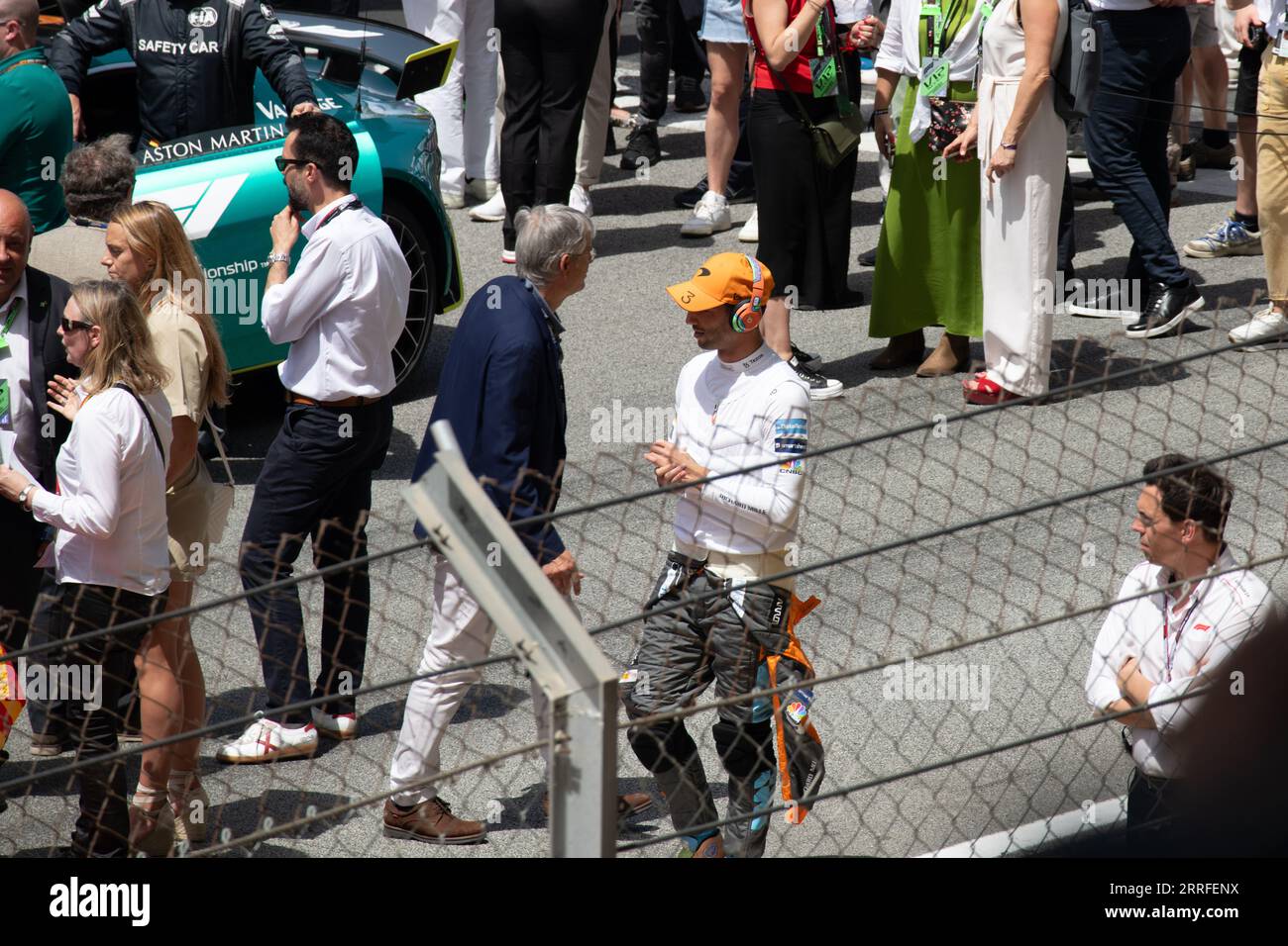 Der F1-Fahrer Daniel Ricciardo wurde vor dem Rennen aufgenommen und sieht sich mit angeschalteten Kopfhörern lässig spazieren. Ein Publikum im Hintergrund trägt zum atm vor dem Rennen bei Stockfoto