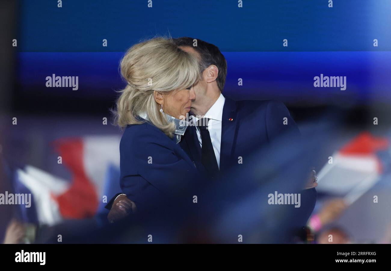 220424 -- PARIS, 24. April 2022 -- der amtierende französische Präsident Emmanuel Macron küsst seine Frau Brigitte Macron bei einer Kundgebung nach dem Präsidentschaftsabsprung in Paris, Frankreich, am 24. April 2022. Der amtierende französische Präsident Emmanuel Macron gewann 2022 mit 58 Prozent der Stimmen den französischen Präsidentschaftsabschlag, so die vorläufige Ausstiegsumfrage, die am Sonntagabend vom französischen Fernsehen BFMTV veröffentlicht wurde. Macrons Rivale, die rechtsextreme Kandidatin Marine Le Pen, gewann 42 Prozent der Stimmen. FRANKREICH-PARIS-PRÄSIDENTENABFLUSS GaoxJing PUBLICATIONxNOTxINxCHN Stockfoto
