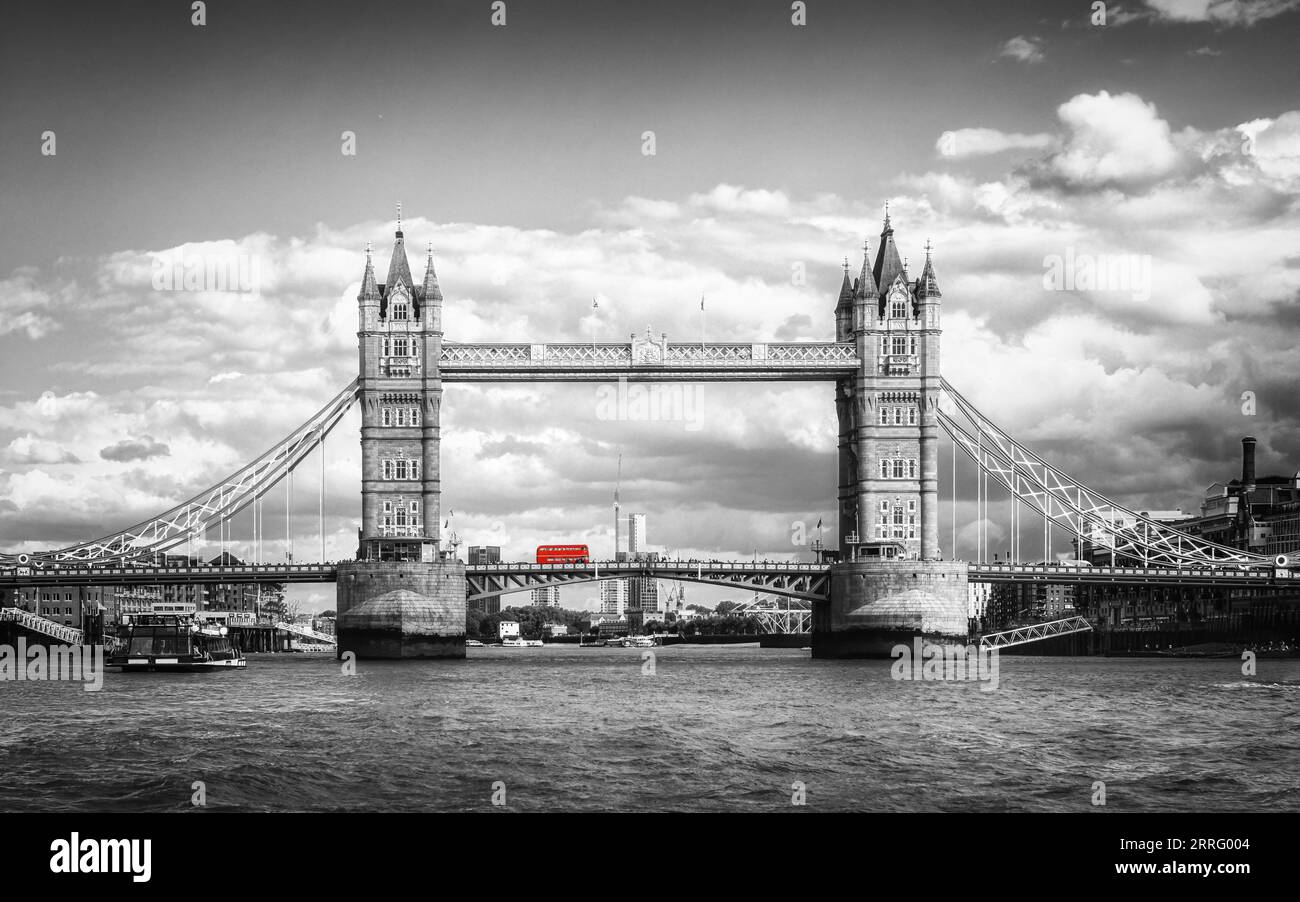 Ein ikonischer roter Londoner Bus, der in einem Schwarz-weiß-Bild hervorgehoben wird, während er über die Tower Bridge auf der Themse in London, England, fährt Stockfoto