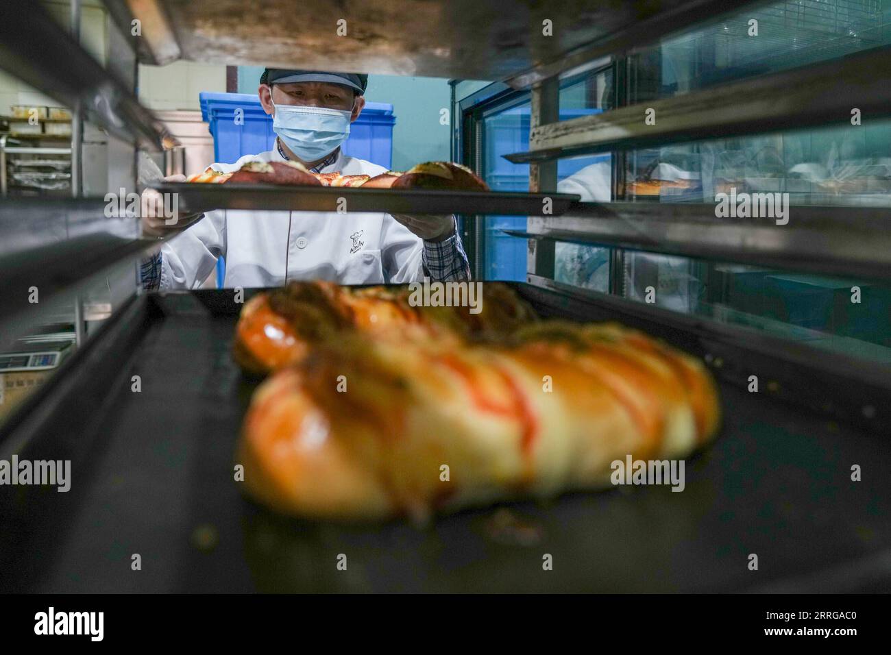 220515 -- NANJING, 15. Mai 2022 -- Ein geistig behinderter Mitarbeiter überträgt Brot in die Amity Bakery in Nanjing, ostchinesische Provinz Jiangsu, 15. Mai 2022. Die 2007 gegründete Bäckerei bietet in den letzten 15 Jahren fast 100 geistig behinderten Menschen Berufsausbildung und Arbeitsmöglichkeiten. CHINA-JIANGSU-NANJING-BÄCKEREI-GEISTIG BEHINDERTE MITARBEITER CN LIXBO PUBLICATIONXNOTXINXCHN Stockfoto