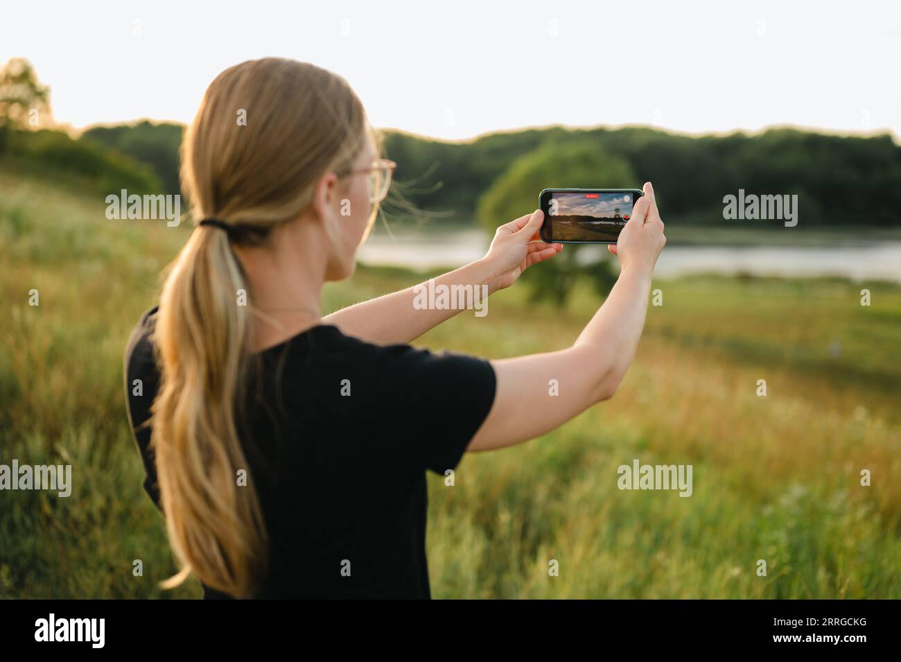 Rückansicht einer Frau, die ein Video auf dem Smartphone der Naturlandschaft macht Stockfoto