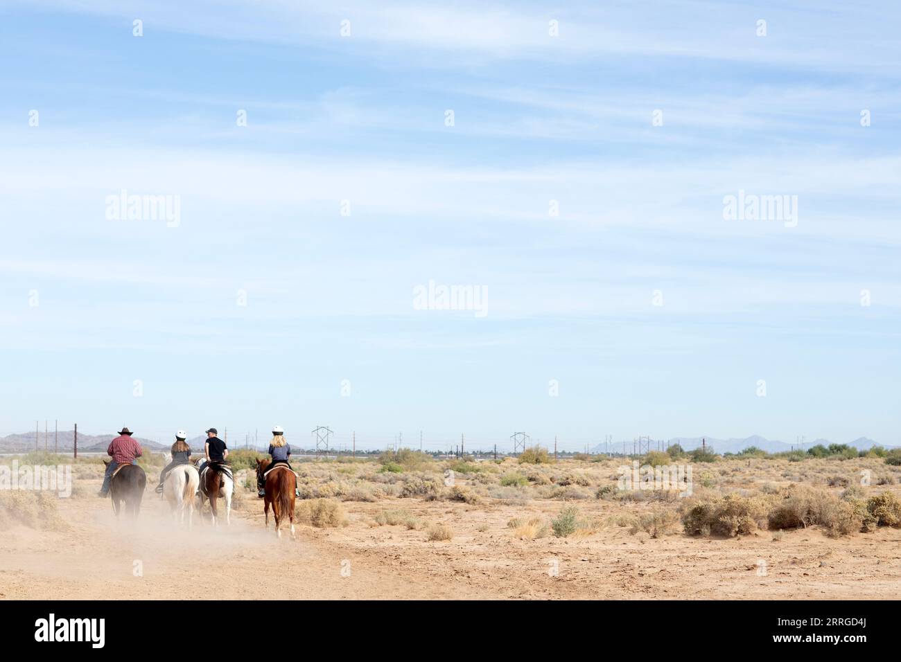 Vier Personen auf dem Pferderücken, die vom Betrachter weggehen Stockfoto