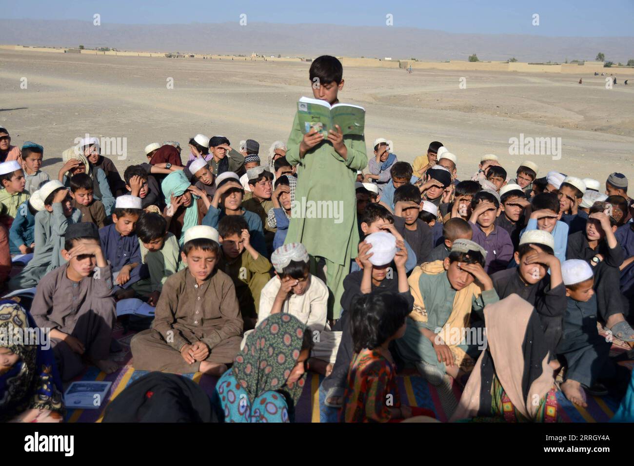 220603 -- KANDHAR, 3. Juni 2022 -- Ein Junge liest während einer Klasse an einer mobilen Schule in der Provinz Kandhar, Afghanistan, 2. Juni 2022. Eine mobile Schule wurde in der afghanischen Provinz Kandhar eingerichtet. Die mobile Schule reist von Dorf zu Dorf, um lokalen Kindern Bildungschancen zu bieten. Foto von /Xinhua AFGHANISTAN-KANDHAR-MOBILE SCHULE SanullahxSeiam PUBLICATIONxNOTxINxCHN Stockfoto