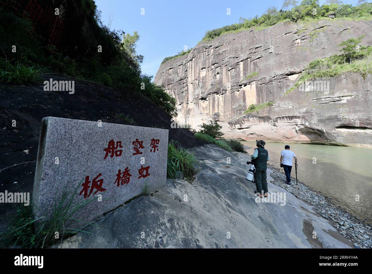 220608 -- WUYISHAN, 8. Juni 2022 -- Touristen besuchen das alte Relikt der Steinhäuser mit hölzernen Bootsärgen des Mount Wuyi in der südöstlichen chinesischen Provinz Fujian, 6. Juni 2022. Der Mount Wuyi in der südöstlichen Provinz Fujian in China ist eine Landschaft von großer Schönheit, in der die Gipfel und Felsen grotesker Formen von klaren Bächen umrahmt und von grünen Bäumen und Bambuspflanzen umgeben sind. Als Lebensraum für eine große Anzahl von Wildtieren ist er von enormer Bedeutung für die Erhaltung der biologischen Vielfalt. Es gibt eine Reihe von außergewöhnlichen archäologischen Stätten am Mount Wuyi, einschließlich der Überreste von Stockfoto