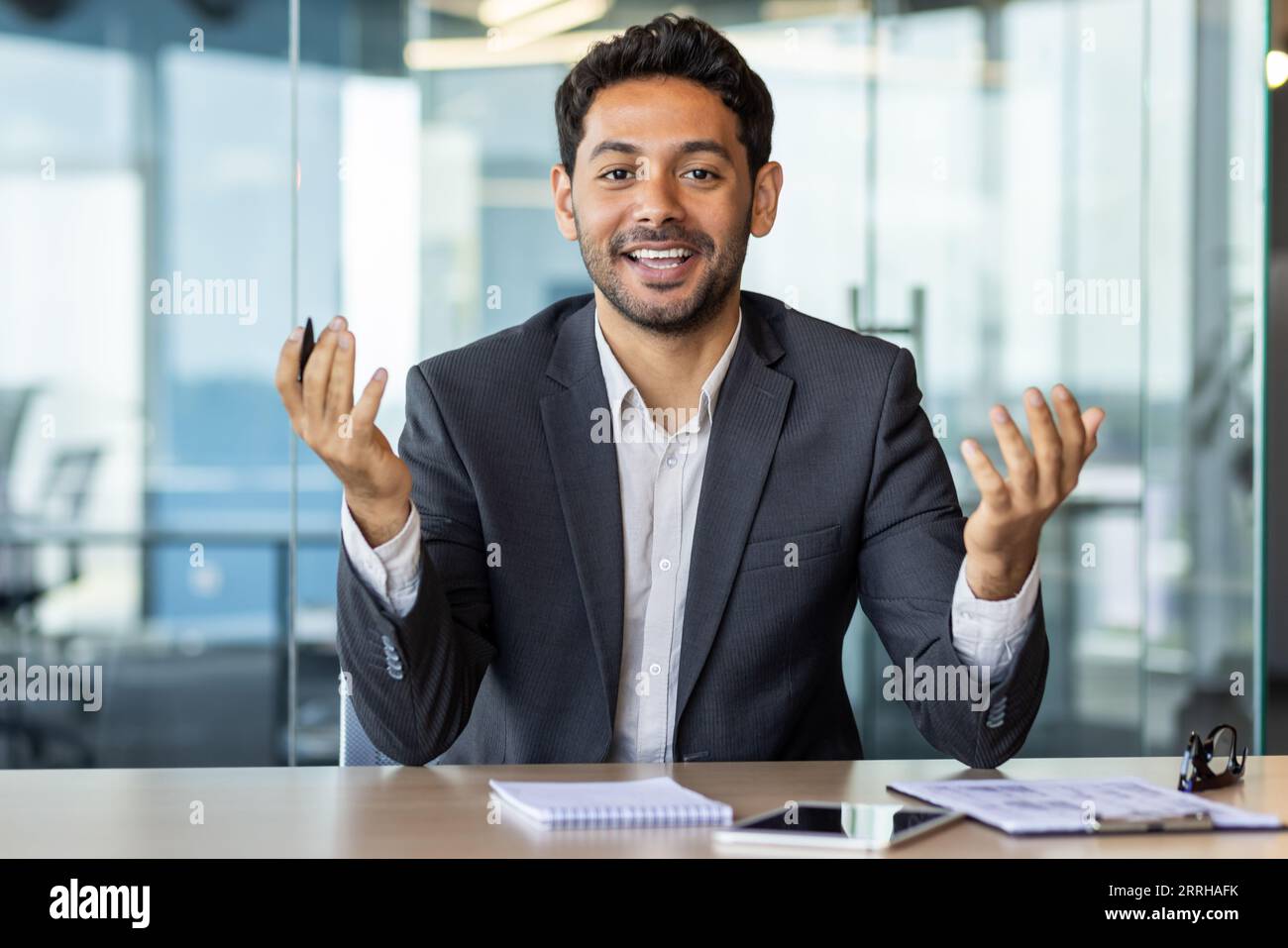 Videoanruf per Webcam ansehen, junger arabischer Mann im Büro, der mit Kollegen aus der Ferne spricht, Mann, der die Kamera ansieht, lächelt am Arbeitsplatz im Büro. Stockfoto