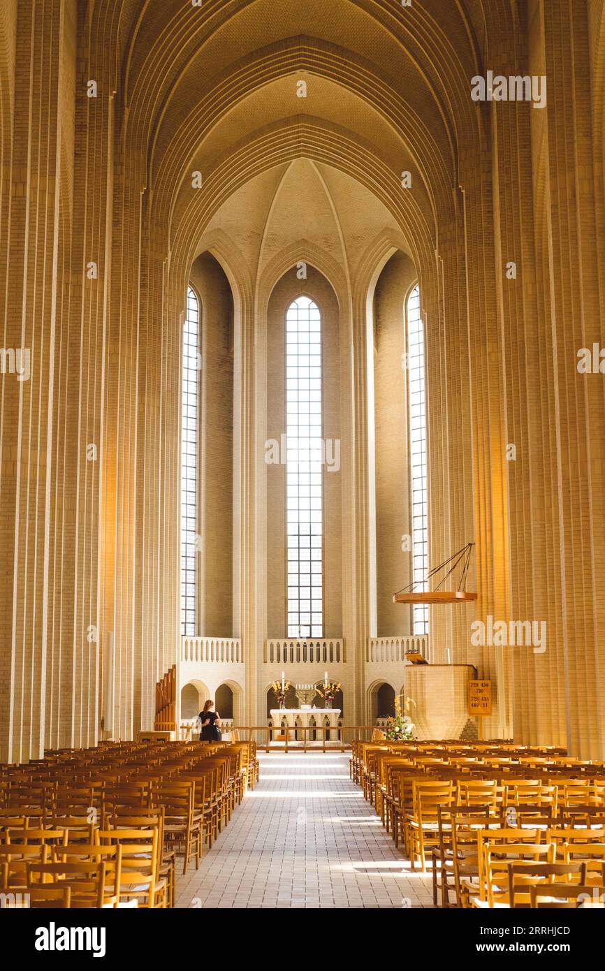 Grundtvigs Kirche ruhiger Blick auf die Bänke mit Holzstühlen und das Heiligtum und den Altar mit extrem hohen Fenstern und Säulen Stockfoto