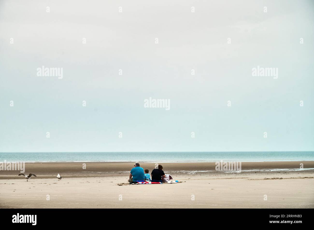 Dreiköpfige Familie an einem etwas leeren Blackpool Strand am Ende des Sommers Stockfoto