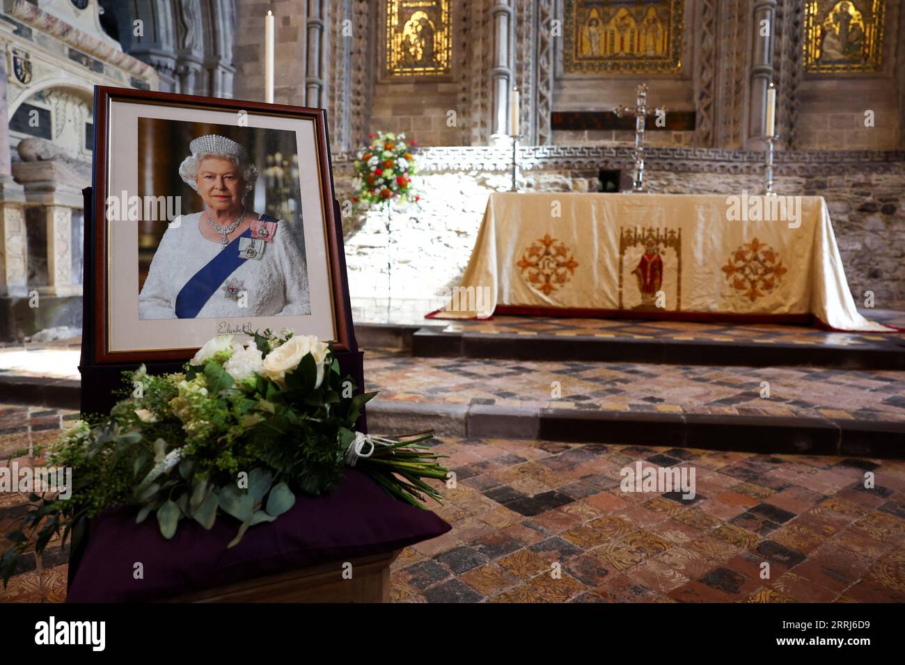 Blumen des Prinzen und der Prinzessin von Wales sind neben einem Porträt der verstorbenen Königin Elisabeth II. Während eines Gottesdienstes in der St Davids Cathedral, Haverfordwest, Pembrokeshire, im Westen von Wales zu sehen, um an das Leben der verstorbenen Königin zu erinnern. Bilddatum: Freitag, 8. September 2023. Stockfoto