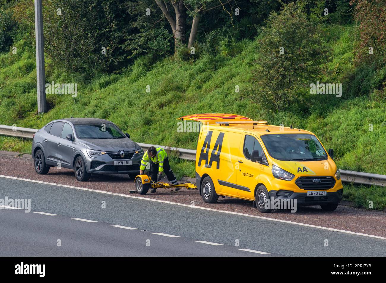 24-Stunden-Pannenhilfe von einem gelben AA-Transporter, da der Autofahrer einen Motorschaden erleidet, ein defektes Fahrzeug, das auf der Autobahn in Manchester, Großbritannien, geparkt ist Stockfoto