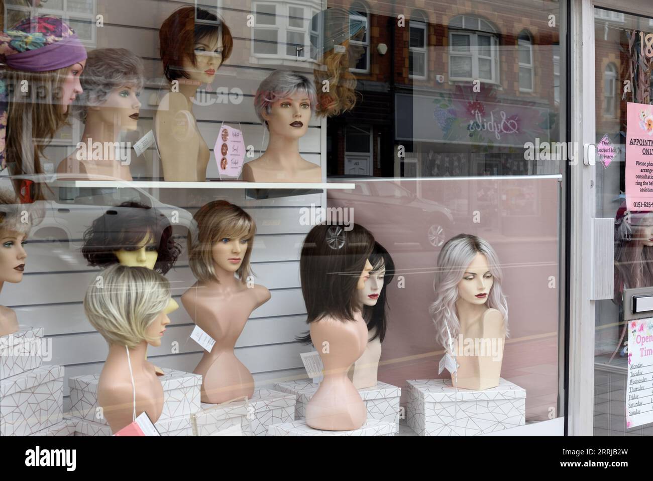 Friseur oder Friseur Schaufenster, Schaufenster oder Schaufenster mit Schaufensterpuppen oder Dummies mit Perücken und Topknoten West Kirby E Stockfoto