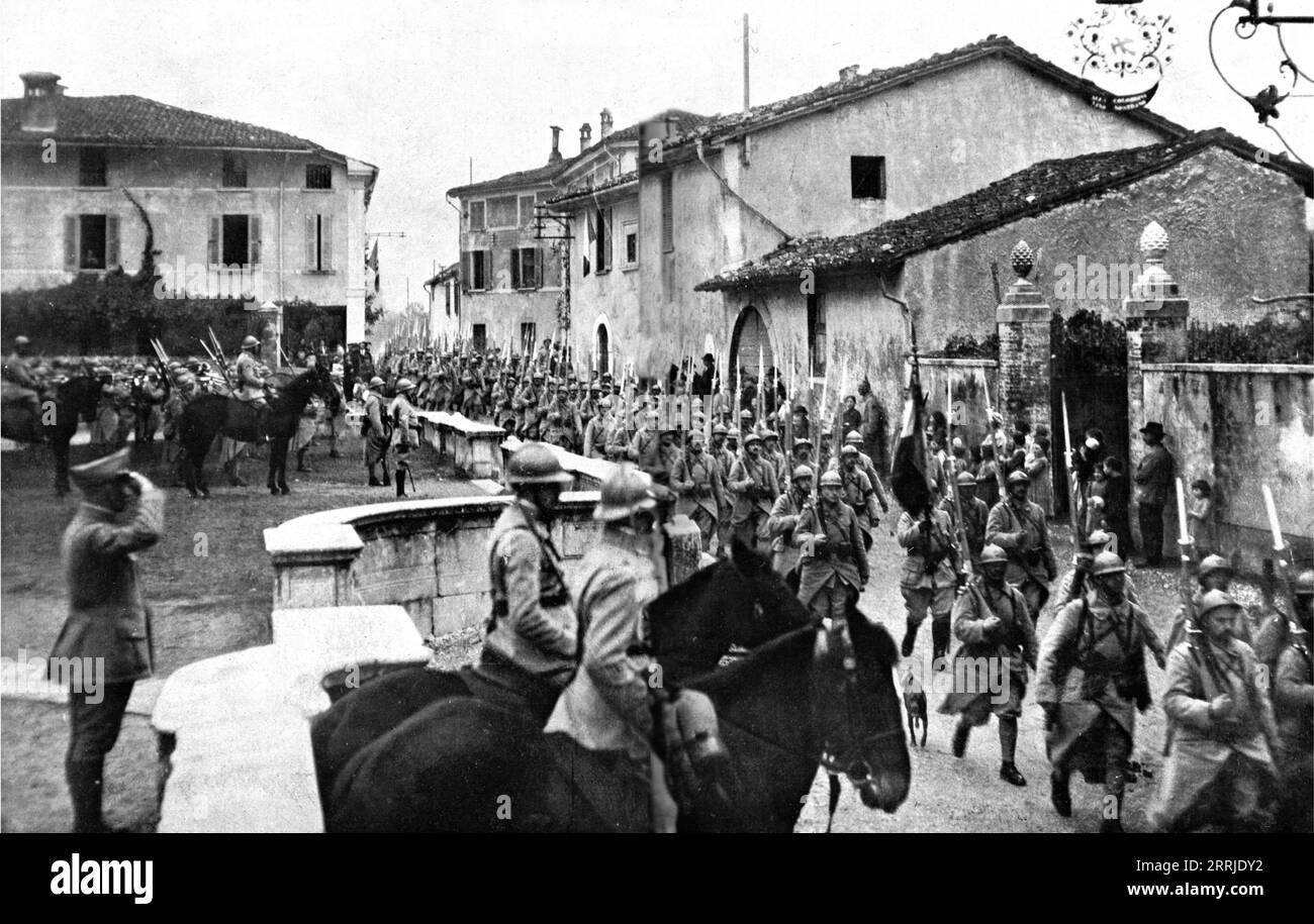 "Ankunft französischer Truppen in Italien; beim Betreten des Dorfes, in dem sie stationiert sind, marschiert ein französisches Regiment an seinem Oberst vorbei", 1917. Aus L’Album de la Guerre 1914-1919, Band 2 [L’Illustration, Paris, 1924]. Stockfoto