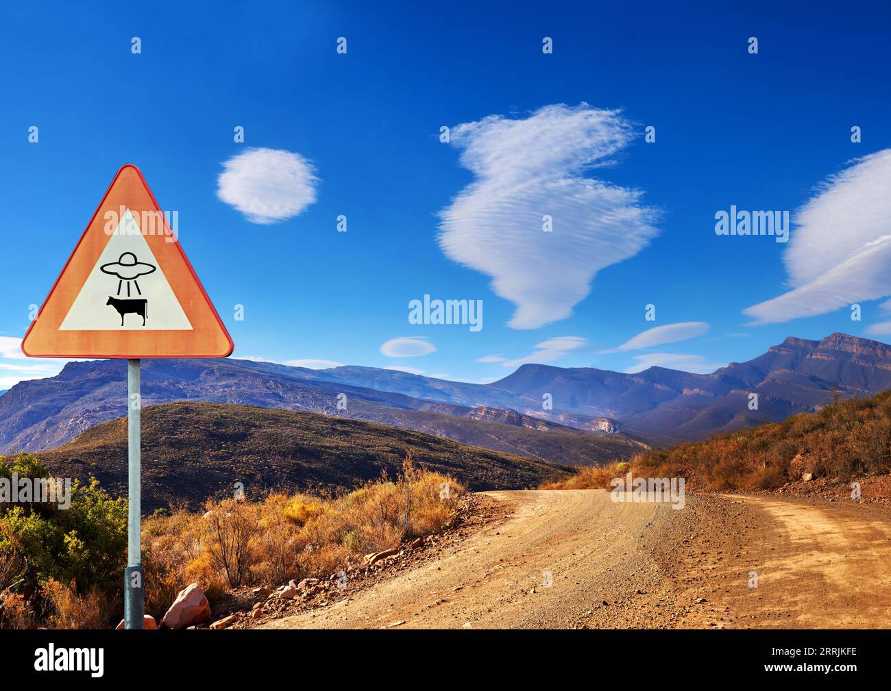 Wüste, Schild und Entführung von Außerirdischen in den Bergen mit einer Ufo-Warnung auf einer unbefestigten Straße am blauen Himmel. Natur, Sommer und eine Route in die Gegend 51 mit Stockfoto