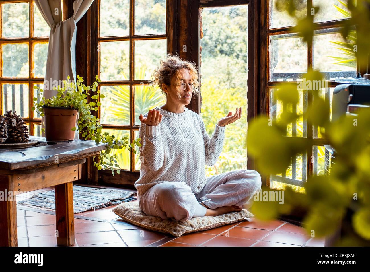 Eine Frau zu Hause in der Halle, die Yoga Asana Meditation Übung für geistige und körperliche Gesundheit. Gesunde und natürliche Lebensweise weibliche Menschen, die auf dem Boden sitzen. Meditation und zenartige Aktivität allein Stockfoto