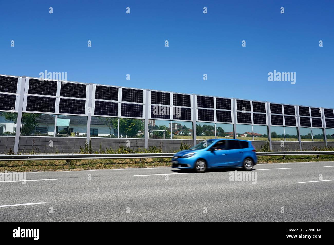 Deutschland, Bayern, Oberbayern, Neuötting, Wohnsiedlung, davor Schallmauer mit Photovoltaik, Straße, vorbeifahrendes Auto Stockfoto