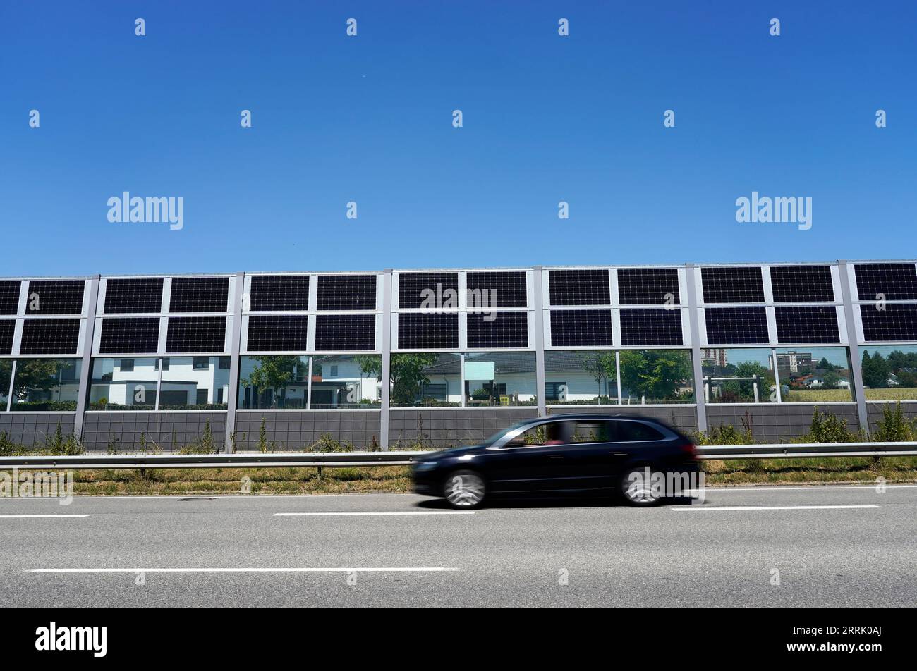 Deutschland, Bayern, Oberbayern, Neuötting, Wohnsiedlung, davor Schallmauer mit Photovoltaik, Straße, vorbeifahrendes Auto Stockfoto