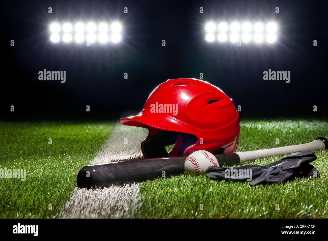 Roter Schlaghelm Fledermaus Baseball und Handschuhe auf dem Rasen mit Streifen unter Stadionbeleuchtung in der Nacht Stockfoto