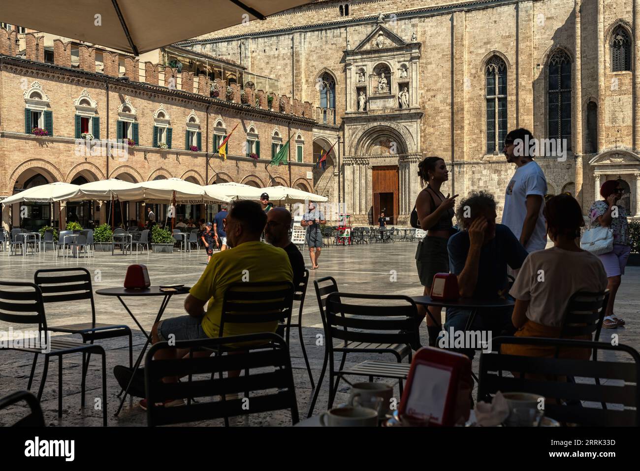 Piazza del Popolo, die Arkaden mit Bars und Restaurants, die an einem heißen Spätsommertag von Touristen überfüllt sind. Ascoli Piceno, Marche Region, Italien, Europa Stockfoto