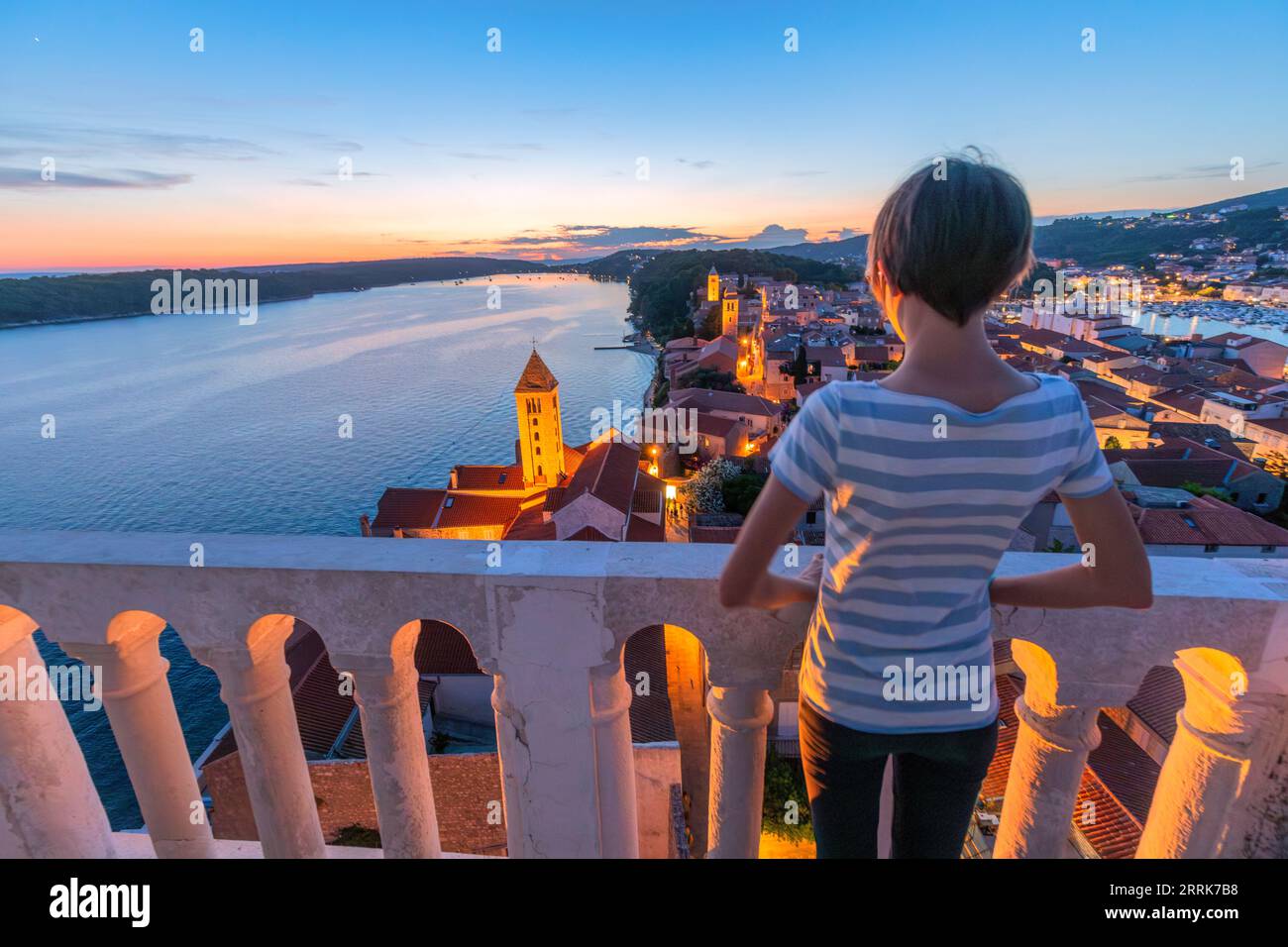 Europa, Kroatien, Primorje-Gorski Komitat Kotar, Insel Rab, junges Mädchen (14 Jahre alt) blickt in der Abenddämmerung auf die Altstadt von Rab Stockfoto