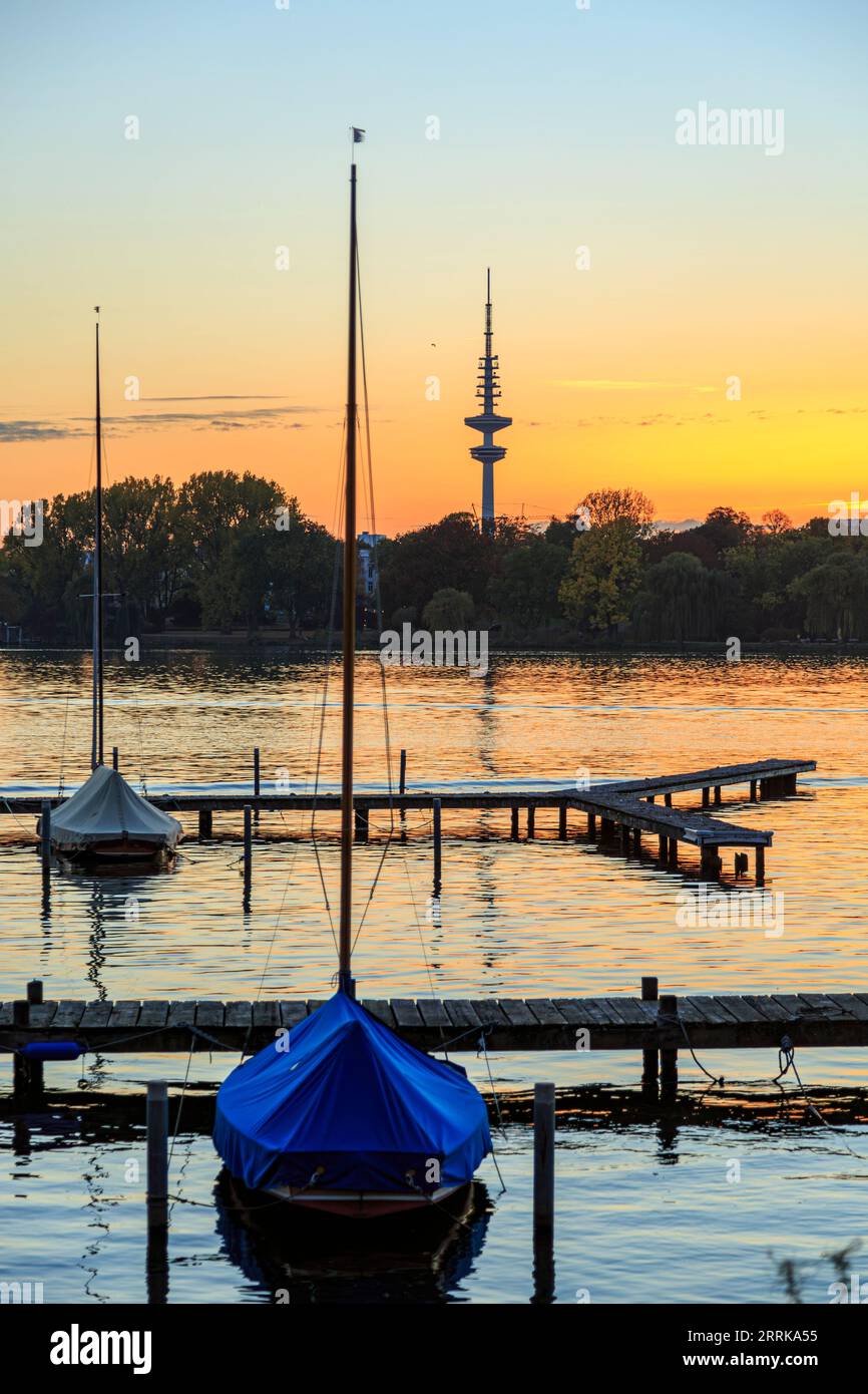 Hamburg, Äußere Alster nach Sonnenuntergang, Segelboote liegen auf dem Steg, Fernsehturm im Hintergrund, orange-roter Himmel, Stockfoto