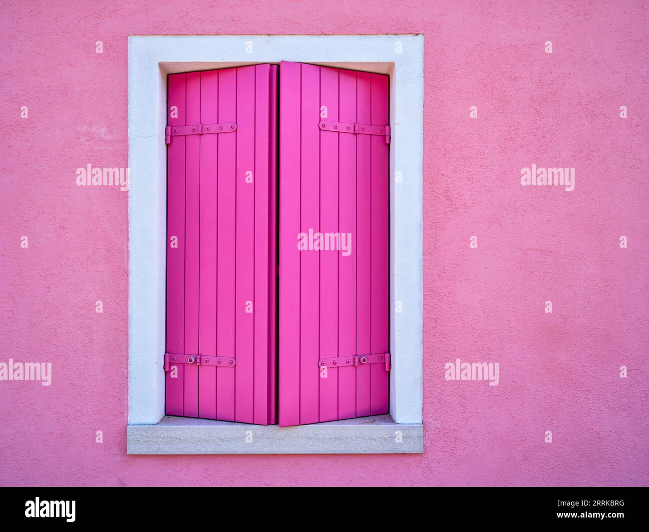 Auf der Straße auf Burano in der Lagune von Venedig, Hausfassade, Fenster, Rollläden, rosa Stockfoto