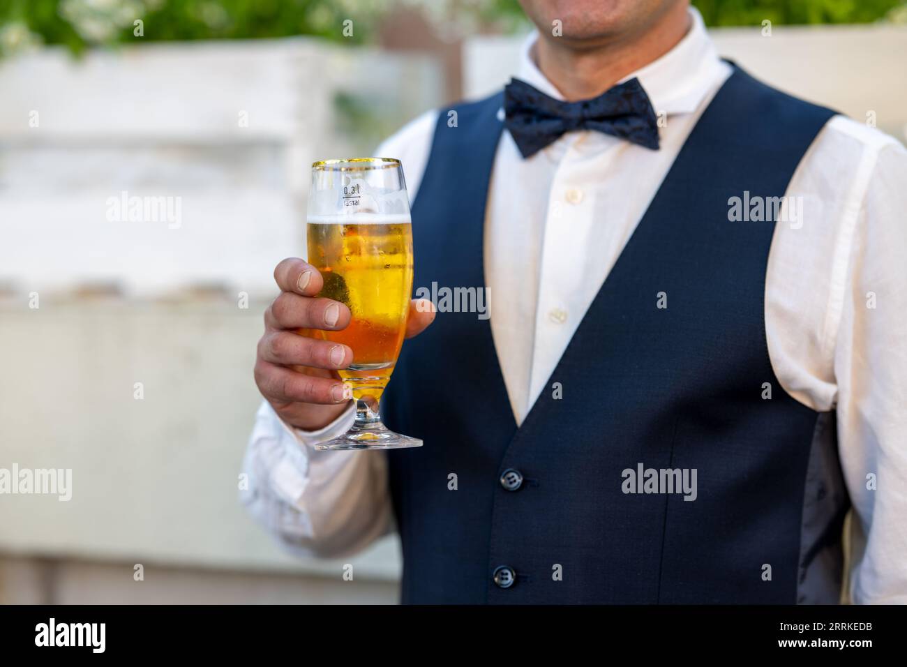 Gesellschaft, September 08. Im Mittelpunkt der Szene steht ein selbstbewusster Mann, der ein Glas Bier in der Hand halten. Er ist formell gekleidet und Stockfoto